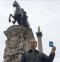 Peter Hitchens holding the letter H, standing with the statues of Nelson and King Charles I